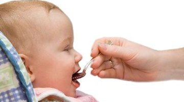 Father feeding baby (6-12 months), indoors