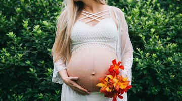 Young woman with a baby boy standing against the wall