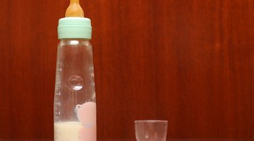 baby with small bottle in bed