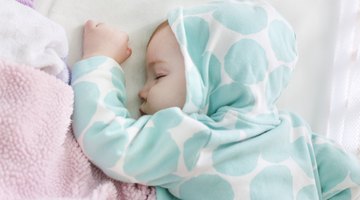 Close-up of a baby boy holding the railing of a crib