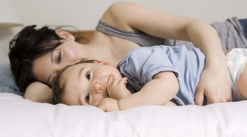 Baby (3-6 months) lying on white sheets, close-up