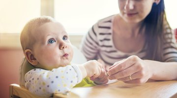Father feeding baby (6-12 months), indoors