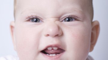 Close-up of a baby boy holding the railing of a crib