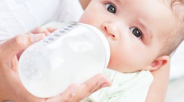 baby with small bottle in bed