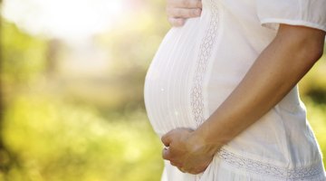 Pregnant woman against blossoming tree in spring