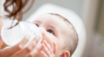 baby with small bottle in bed