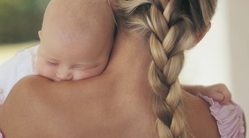 Happy mother with her newborn baby on bed