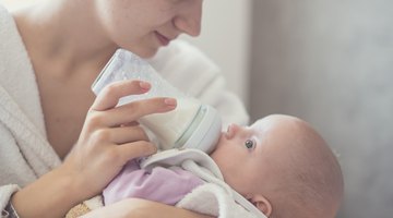 baby with small bottle in bed
