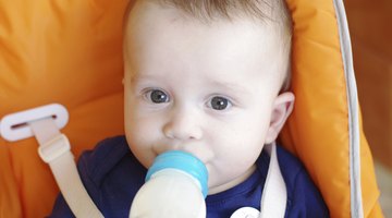 baby with small bottle in bed