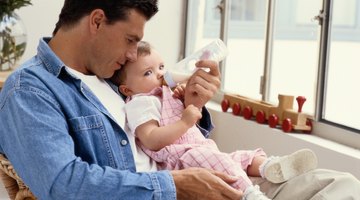 Close-up of a baby drinking milk in his mother's arms