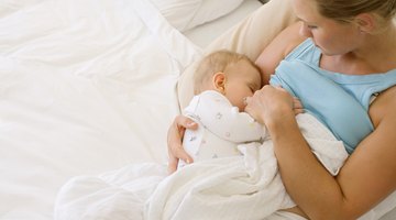 young mother breast feeding her baby girl at sunny day