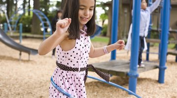 Five children (7-11) running with plastic hoops in park (surface level)